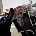 A protester tears a defaced poster of Yemeni President Saleh during a demonstration in Sanaa University